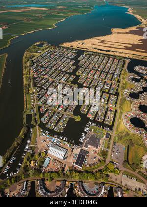 Luftaufnahme einer Wohnanlage am Wasser und Yachthafen mit Booten am Rande eines großen Sees in Lemmer, Friesland, Niederlande. Stockfoto