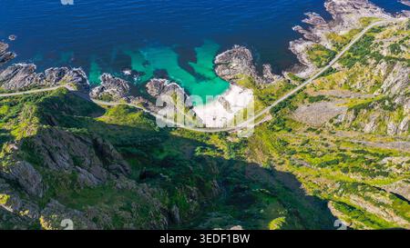 Dieses spektakuläre Drohnenfoto zeigt eine der berühmtesten Szenen Norwegens, eine kurvige Straße, die in den felsigen Rand eines Lofoten-Berges gehauen wurde Stockfoto