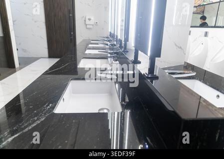 Eleganter Schminktisch aus schwarzem Marmor mit mehreren Waschbecken in einem modernen Badezimmer, mit eleganten Armaturen, heller Beleuchtung und stilvoller Inneneinrichtung Stockfoto