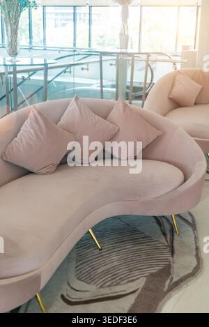Dieses Bild zeigt ein elegantes pinkfarbenes Sofa mit Kissen in einem modernen Innenraum, das modernes Design und eine stilvolle Einrichtung bietet, die ideal für Familien ist Stockfoto