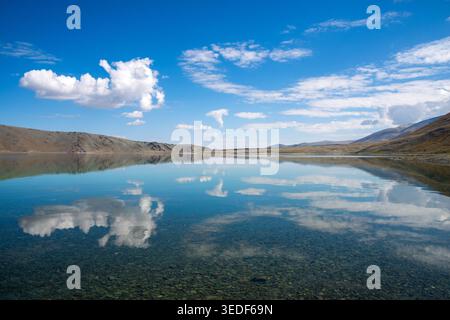 Eine Weitwinkelaufnahme eines hochalpinen Sees in der Westmongolei. Das stille, transparente Wasser zeigt im Vordergrund ein felsiges Seebad Stockfoto