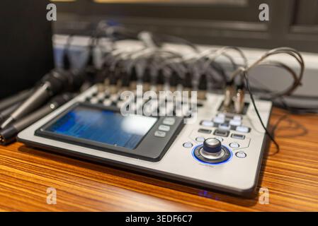 Nahaufnahme eines Audiomischpults mit zahlreichen Kabeln und einem Mikrofon, das die wichtigsten Geräte für die Musik- und Tonproduktion zeigt Stockfoto