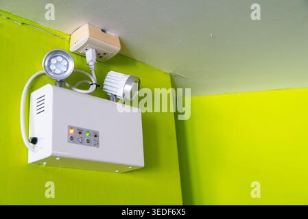 Dieses Bild zeigt moderne Deckenleuchten, die an einer leuchtend grünen Wand montiert sind und stilvolle Bedienelemente für Beleuchtung und Energieeffizienz hervorheben Stockfoto