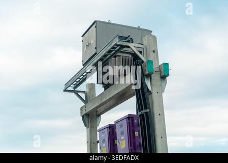 Eine detaillierte Ansicht eines elektrischen Transformators, der auf einer Betonkonstruktion montiert ist und moderne Industrietechnologie für die Stromverteilung A zeigt Stockfoto