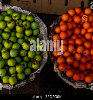Ein Blick von oben auf frische grüne Äpfel und helle Orangen in traditionellen Korbkörben auf einem Obstmarkt in Dhaka, Bangladesch. Stockfoto
