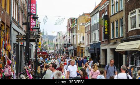 Die Menschenmassen bewegen sich entlang einer belebten Einkaufsstraße mit Ladenfronten, Outdoor-Displays und einer lebhaften urbanen Atmosphäre. Stockfoto