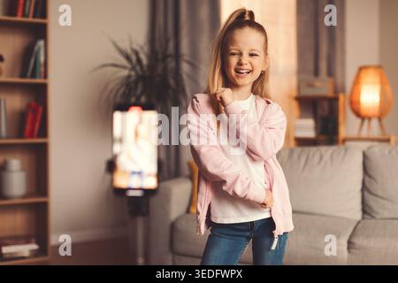 Mädchen tanzt und lächelt im Wohnzimmer während eines Videogesprächs mit der Familie Stockfoto