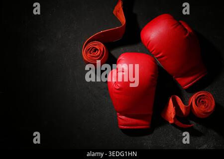 Paar rote Boxhandschuhe mit Armbändern auf schwarzem Hintergrund Stockfoto