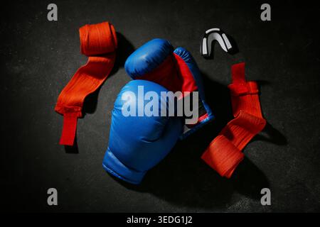 Ein Paar blaue Boxhandschuhe mit Armbändern und Mundstück auf schwarzem Hintergrund Stockfoto