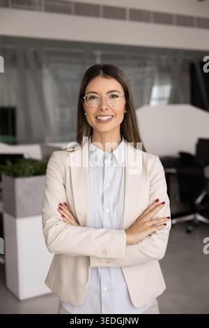 Lächelnde Geschäftsfrau in elegantem Anzug posiert im modernen Büro Stockfoto