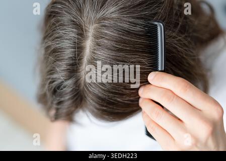 Nahaufnahme einer Frau, deren graues Haar von ihrem langen Kampf mit Depressionen stammt. Der reife Erwachsene sieht körperliche Manifestation von mentalen Schmerzen in Strängen. Mutter spürt Silber auf Leid. Stockfoto