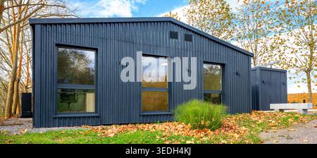Nachhaltiger Versandcontainer modernes Haus mit Wellblechverkleidung im Herbst Stockfoto
