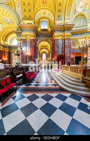 Die Menschen versammeln sich bei Tageslicht in der Stephansbasilika in Budapest, Ungarn. Die schöne Innenausstattung zeigt satte Details und Farben. Stockfoto
