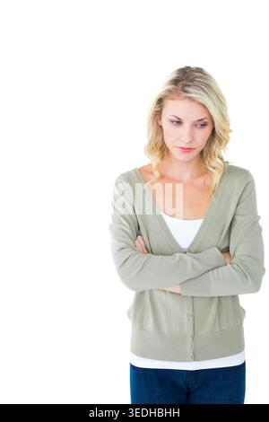 Frau, die mit überkreuzten Armen steht, im Studio nach unten blickt, in grüner Strickjacke, Jeans, Kopierraum. Blond, nachdenklich, Denim, Hintergrund, Highkey, minimal Stockfoto