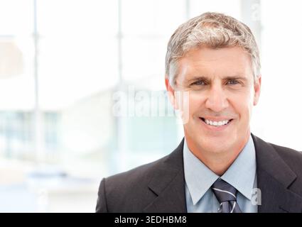 Mann mittleren Alters lächelt, posiert für Kopfschuss im Firmenbüro mit Anzug und gestreifter Krawatte. Porträt, Executive, Professional, Business, modern Stockfoto