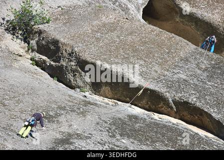 Bergsteiger, die an einem sonnigen Tag auf einer texturierten Klippenseite navigieren, Meteora, Kalabaka, Thessalien, Griechenland, Europa Stockfoto