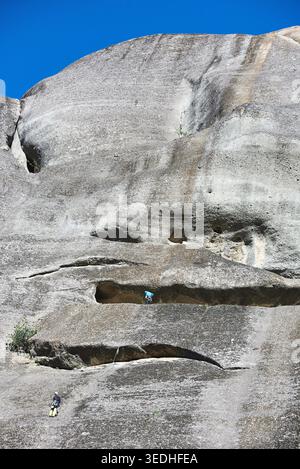 Weite Sicht auf zwei Bergsteiger auf einem massiven vertikalen Konglomerat-Felsenturm unter einem klaren blauen Himmel, Meteora, Kalabaka, Thessalien, Griechenland, Europa Stockfoto