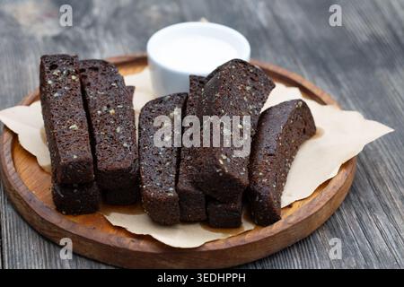 Schwarzer Knoblauchbrot mit weißer Sauce auf einem Holzbrett. Stockfoto