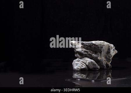 Stein Podium mit Wasser als Ufer in der Nacht für die Darstellung von Verpackung und Produkt auf dunkelschwarzem Hintergrund. Stockfoto