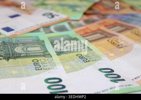 Mehrere Euro-Banknoten sind auf einer Ebenen Fläche verteilt und zeigen Banknoten verschiedener Stückelungen. Die Notizen enthalten Entwürfe mit Gebäuden und Sym Stockfoto