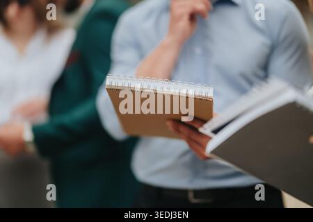 Geschäftsleute halten Notizbücher und machen sich Notizen während eines Meetings in einem professionellen Umfeld Stockfoto