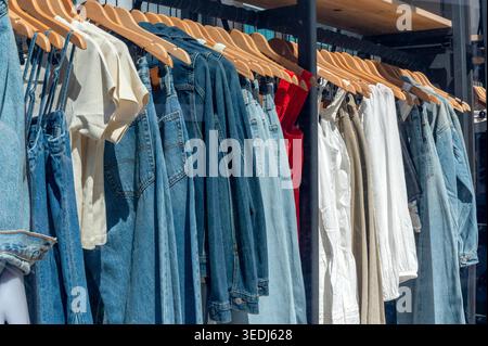 Stilvolle Kleidungsstücke hängen an Holzbügeln und bieten eine Vielfalt zum Verkauf im Einzelhandel Stockfoto