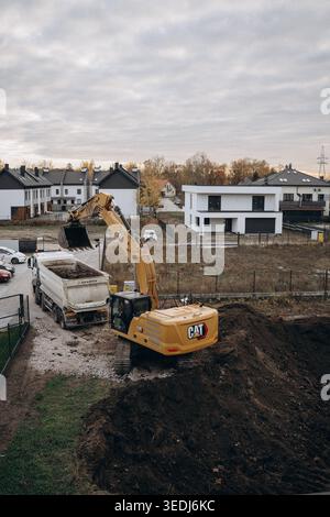 Orangefarbener Bagger beim Graben einer Grundgrube für den Wohnbau. Draufsicht, vertikale Luftaufnahme bei Arbeiten mit schweren Maschinen Stockfoto
