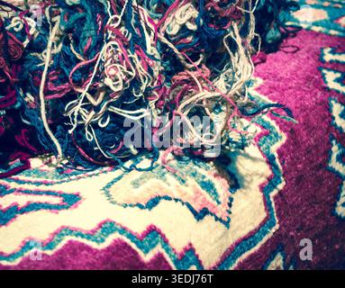 Orientalische Teppiche und Wollfäden auf dem Markt. Konzept „vom Material zum Produkt“. Selektiver Fokus auf die Gewinde. Getöntes Foto. Stockfoto