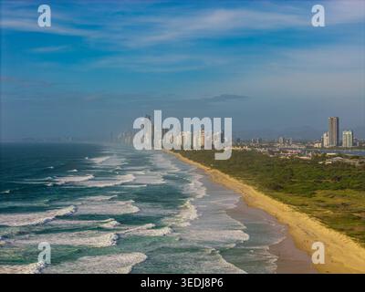 Ein atemberaubendes Luftbild fängt die pulsierende Skyline der Gold Coast ein, die sich entlang eines unberührten Sandstrandes und türkisfarbener Meereswellen erstreckt. Stockfoto