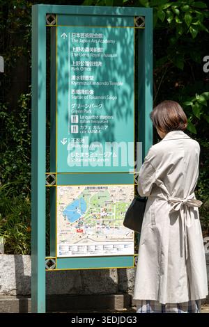 Tokio, Japan 14. April 2026 Außenansicht einer Person, die vor einer grünen Richtungstafel im ueno Park steht und eine Karte und eine Flosse liest Stockfoto