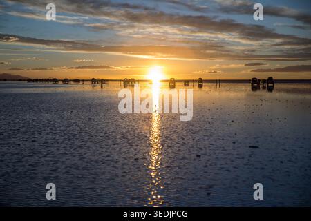 Die Sonne untergeht dramatisch über dem Salar de Uyuni, der größten Salzebene der Welt im Departement Potosí in Bolivien, als dünne Wasserschicht Stockfoto