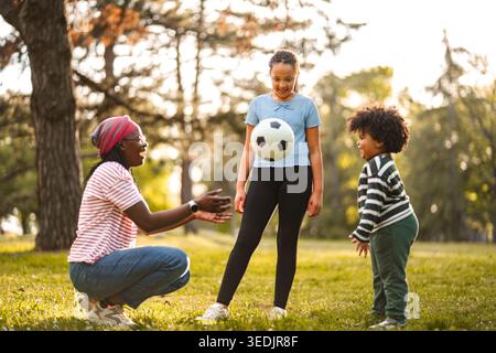 Mutter und Kinder spielen Fußball im Park Stockfoto