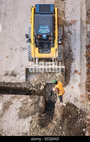 Straßenreparaturarbeiten. Planierschild oder Lader bewegt sich und nivelliert die Erde auf der Baustelle. Schwere Baumaschinen für Erdarbeiten. Ein Gleitschuh Stockfoto