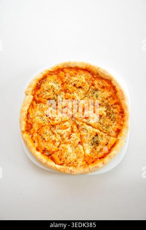 Handgemachte Pizza in Pfannenform mit Tomatensauce, Fleisch- und Käsebelag, serviert auf einem Teller auf einem weißen Tisch Stockfoto
