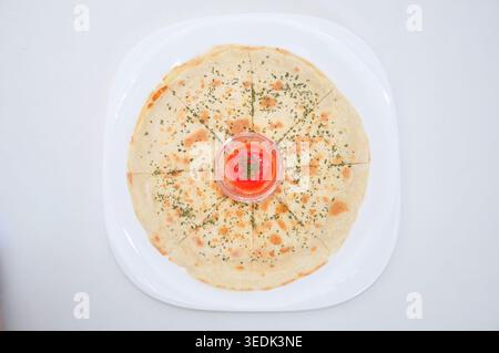 Eine frisch gegrillte Quesadilla mit Chili-Sauce, serviert auf einer weißen Platte mit weißem Hintergrund Stockfoto