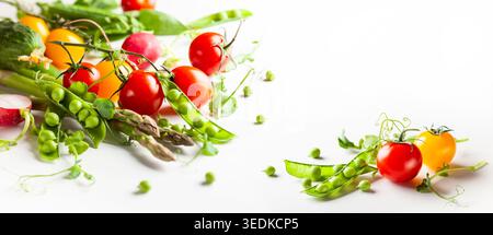 Frische grüne Erbsenschoten mit Sprossen, Rettich, Tomaten und grünem Spargel auf weißem hölzernem Hintergrund. Konzept der gesunden Ernährung, frisches Gemüse. Stockfoto
