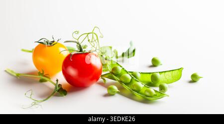 Frische grüne Erbsenschoten mit Sprossen und Kirschtomaten auf weißem hölzernem Hintergrund. Konzept der gesunden Ernährung, frisches Gemüse. Stockfoto