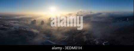 Aus der Vogelperspektive auf Hochhäuser und Wohndächer, die aus dickem Morgennebel unter der hellen Sonne in Tübingen, Baden-Württemberg, auftauchen Stockfoto