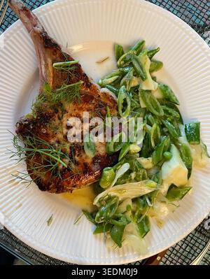 Gourmet-Vorspeise aus gewürztem Schweinekotelett mit Knabbererbsen-Slaw auf einem weißen porzellanteller, 2026, USA Stockfoto