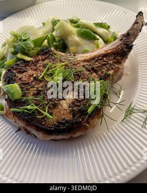 Gourmet-Vorspeise aus gewürztem Schweinekotelett mit Knabbererbsen-Slaw auf einem weißen porzellanteller, 2026, USA Stockfoto