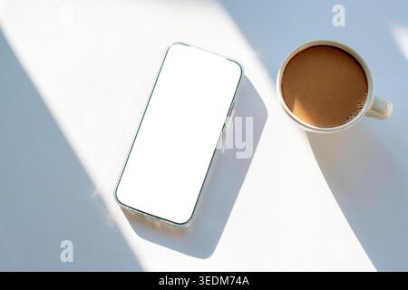 Minimale flache Lage mit Mobiltelefon und Kaffeetasse auf weißem Hintergrund mit Schatten. Draufsicht, Modell. Stockfoto