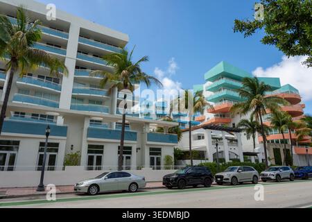 Farbenfrohe moderne Apartmentgebäude im Art déco-Stil und Luxusautos, die unter Palmen in Miami Beach, Florida, geparkt werden. Eine lebendige urbane Szene. Stockfoto