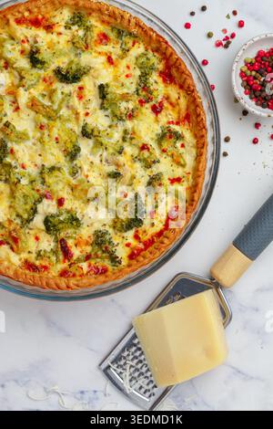 Quiche Lorraine mit Huhn und Brokkoli auf Marmorhintergrund Nahaufnahme. Kuchen mit Gemüse, Geflügel, Käse, Petersilie und Gewürzen. Traditionelles Französisch Stockfoto