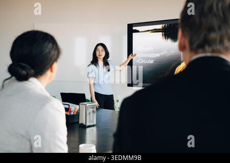 Junge weibliche Angestellte, die Investoren im Sitzungssaal im Büro präsentiert Stockfoto