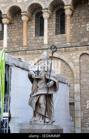St. Bonifatius Statue mit Kreuz und crozier, neben den historischen romanischen Steinmauern des Mainzer Doms Stockfoto