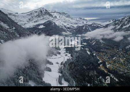 Aus der Vogelperspektive auf Les Rives und das schneebedeckte Alpental mit Nebel über Kiefernwäldern und zerklüfteten Gipfeln in Champery, Wallis, Schweiz. Stockfoto