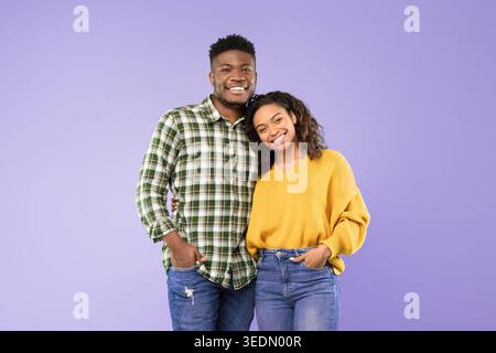 Ein lächelndes Paar posiert in einem zwanglosen Moment vor einem violetten Hintergrund Stockfoto