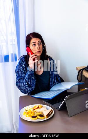 Frau, die per Fernzugriff arbeitet und frühstückt Stockfoto