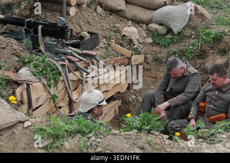 Preußische Soldaten ruhten in der Nähe einer Maxim MG 08 Maschinengewehrposition in einem befestigten Graben während einer historischen Nachstellung des Ersten Weltkriegs. Stockfoto