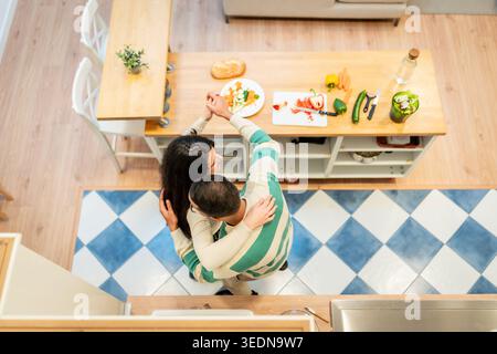 Liebevolles Paar tanzt in der Küche und bereitet gesunde Mahlzeiten vor Stockfoto